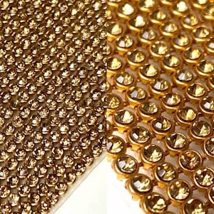 May include: Gold rhinestone mesh fabric. The fabric is made of small, round rhinestones that are set in a mesh backing. The rhinestones are closely spaced together, creating a shimmering effect.