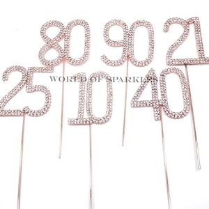 May include: Set of six rhinestone cake toppers in the numbers 25, 40, 10, 80, 90, and 21. The numbers are made of rhinestones and are attached to gold-colored wires.