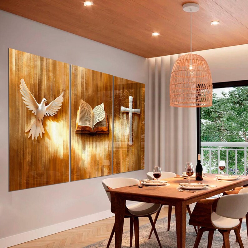 K&ouml;nnte beinhalten: Ein dreiteiliges Wandkunstwerk mit religi&ouml;sen Symbolen: eine wei&szlig;e Taube, ein offenes Buch und ein Kreuz. Das Kunstwerk ist vor einem warmen, h&ouml;lzernen Hintergrund platziert und schafft eine friedliche Atmosph&auml;re. Der Essbereich umfasst einen Holztisch und St&uuml;hle.