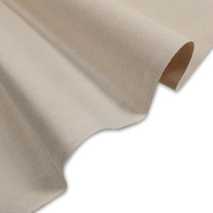 Può includere: Primo piano di un tessuto di tela naturale di colore avorio. Il tessuto ha una texture liscia e uniforme e una leggera lucentezza.
