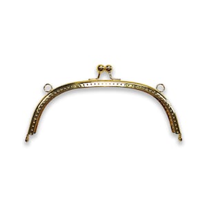 Op de afbeelding: Gouden metalen tasframe met twee ronde knoppen aan de bovenkant en twee lussen aan de zijkanten.