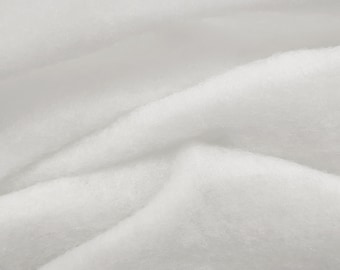 Pode incluir: Tecido branco com uma textura macia e felpuda. O tecido está dobrado e enrugado, criando um fundo texturizado.