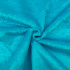 May include: A vibrant turquoise faux fur fabric featuring a dense, soft pile texture. The material is gathered in the center, creating natural folds and shadows that highlight the bright, saturated blue-green color and the plush, fuzzy surface.