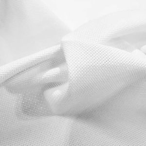 Puede incluir: Primer plano de tela blanca con tejido texturizado. La tela está doblada y drapeada, creando sombras y reflejos. El material parece suave y ligero, posiblemente algodón o lino.