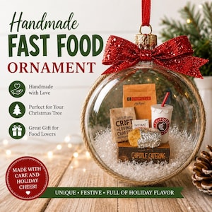 May include: A clear glass Christmas ornament filled with miniature fast food items, including a drink, a burrito, and a bag of chips. The ornament has a red glittery bow and the text "Handmade Fast Food Ornament."