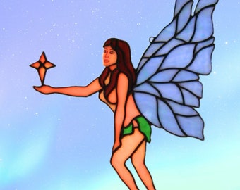 May include: A stained glass fairy with blue wings holding a star. The fairy has long brown hair and is wearing a green skirt. The background is a light blue with white dots.