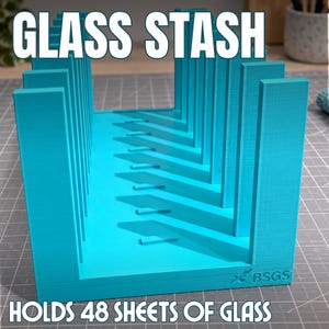 May include: A bright turquoise storage rack for glass sheets with vertical dividers and a flat base. The text GLASS STASH is at the top and HOLDS 48 SHEETS OF GLASS is at the bottom. The brand name BSGS is embossed on the lower right corner.