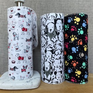 K&ouml;nnte beinhalten: Drei Papierrollen mit verschiedenen Hunde-Designs. Die erste Rolle hat einen wei&szlig;en Hintergrund mit roten, schwarzen und wei&szlig;en Hunden. Die zweite Rolle hat einen wei&szlig;en Hintergrund mit schwarzen und wei&szlig;en Hunden. Die dritte Rolle hat einen schwarzen Hintergrund mit bunten Pfotenabdr&uuml;cken.