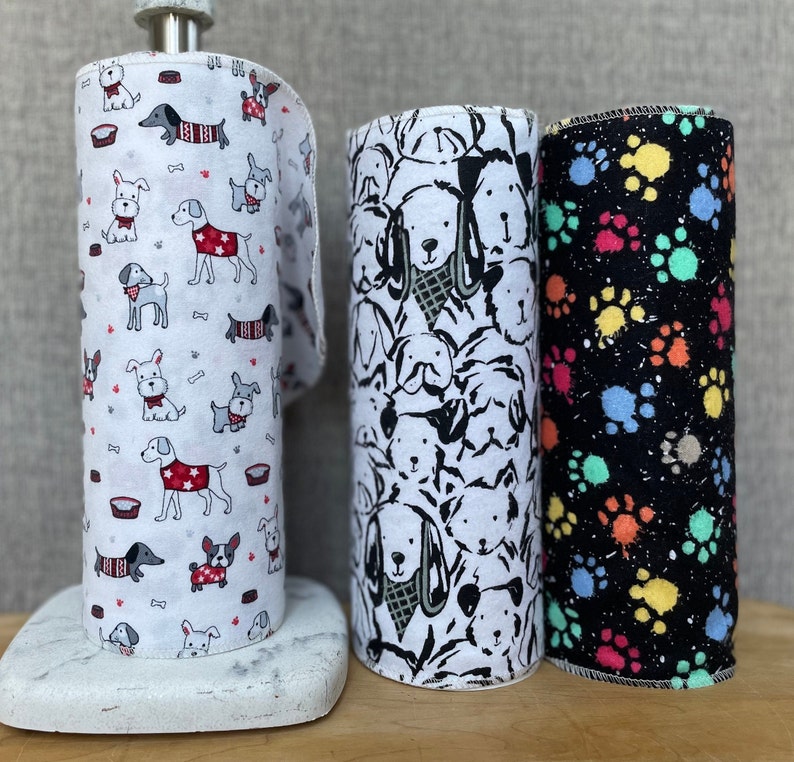 K&ouml;nnte beinhalten: Drei Papierrollen mit verschiedenen Hunde-Designs. Die erste Rolle hat einen wei&szlig;en Hintergrund mit roten, schwarzen und wei&szlig;en Hunden. Die zweite Rolle hat einen wei&szlig;en Hintergrund mit schwarzen und wei&szlig;en Hunden. Die dritte Rolle hat einen schwarzen Hintergrund mit bunten Pfotenabdr&uuml;cken.