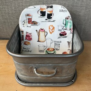 May include: A gray metal container with a handle, featuring a white fabric liner with a coffee-themed print. The print includes coffee cups, coffee beans, and the words "Milk", "Sugar", "White", and "Cafe au lait".