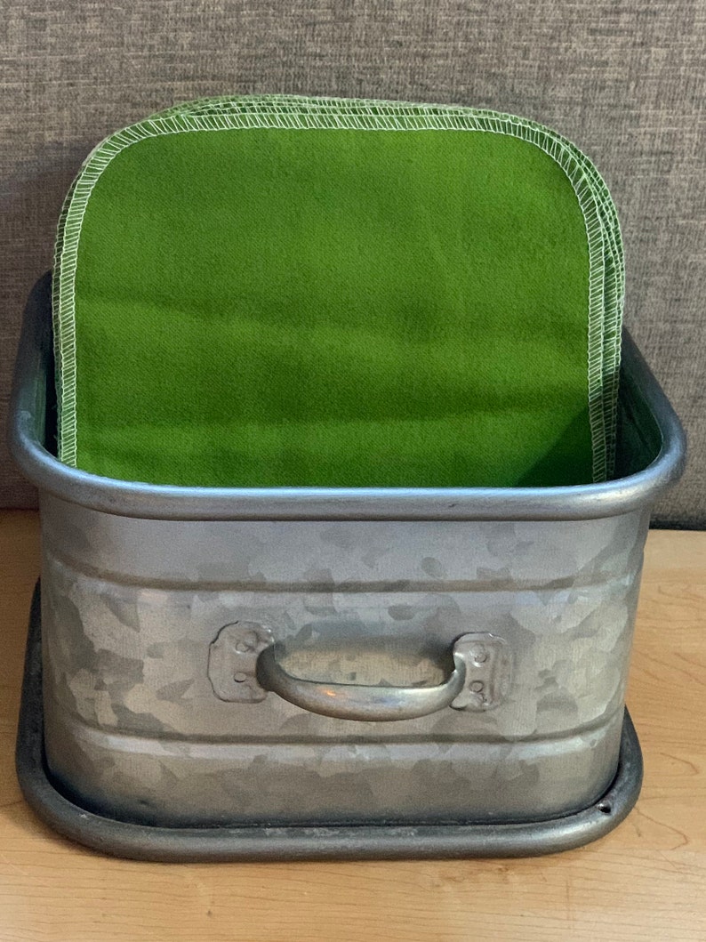 May include: A galvanized metal planter with a handle, filled with a stack of green fabric squares.