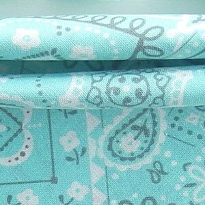 May include: A turquoise fabric with a white and gray paisley pattern.