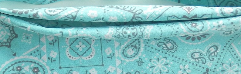 May include: A turquoise fabric with a white and gray paisley pattern.