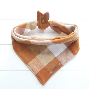 May include: A brown and white plaid dog bandana with a brown leather tag that says "Chumleys".