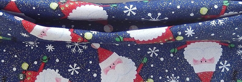 May include: Blue fabric with a repeating pattern of Santa Claus figures and snowflakes. The fabric has a glittery finish.