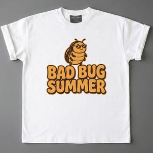 Könnte beinhalten: Ein weißes T-Shirt mit kurzen Ärmeln und einer Grafik eines Zeichentrick-Käfers mit Sonnenbrille. Unter dem Käfer ist der Text BAD BUG SUMMER in fetten, orangefarbenen Buchstaben im Blasen-Stil mit dunkelbrauner Umrandung aufgedruckt.