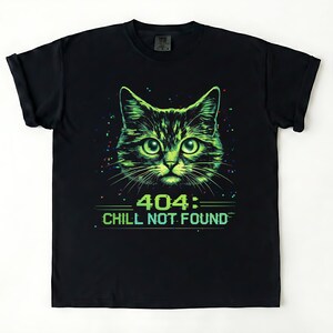 Puede incluir: Camiseta negra con un diseño de cara de gato verde y negro. El gráfico incluye el texto "404: CHILL NOT FOUND" en verde. Los ojos del gato son de color verde brillante y el diseño tiene un efecto pixelado.