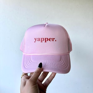 May include: Pink trucker hat with a red "yapper." embroidered on the front.