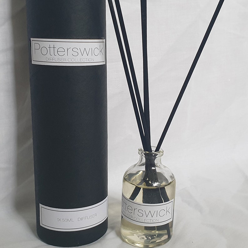 May include: A clear glass diffuser bottle with black reeds and a black cylindrical box. The bottle contains a light-coloured liquid and a label that reads "Potterswick Diffuser Collection". The box also has a label with the same text.