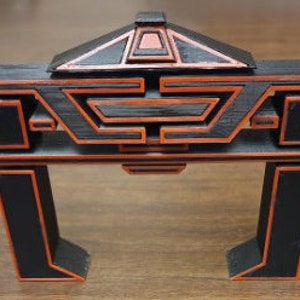 May include: A black and red 3D printed archway with a geometric design. The archway has a layered design with a small roof on top.