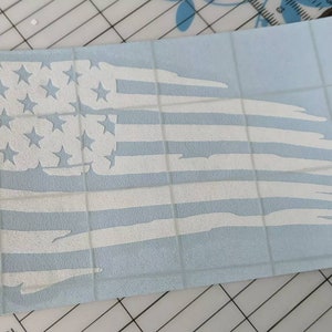 May include: A white distressed American flag decal on a blue background. The flag is tattered and torn, giving it a vintage look.
