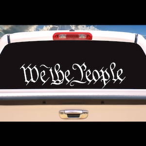 May include: A white "We the People" decal on the back window of a pickup truck.