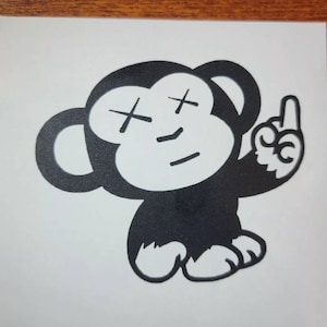 May include: Black and white cartoon illustration of a monkey with an X for eyes, a smile, and one finger raised in the air.