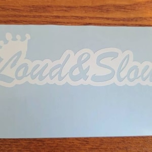 May include: White vinyl sticker with a crown and the text "Loud & Slow" in a cursive font.