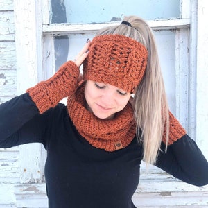 May include: A rust-colored crochet headband, cowl, and fingerless gloves set. The headband has a braided design and the cowl is a simple, wide band.