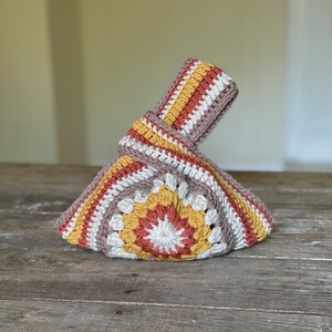 Crochet sunburst knot bag pattern. This beautiful motif crochet pattern is versatile and functional. This boho crochet bag pattern features a crochet flower sunburst design that makes this boho handbag really stand out.