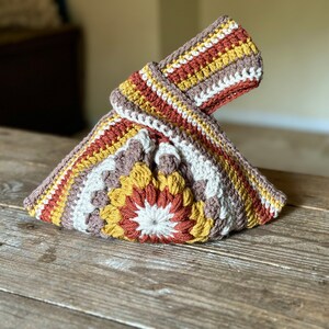 Crochet sunburst knot bag pattern. This beautiful motif crochet pattern is versatile and functional. This boho crochet bag pattern features a crochet flower sunburst design that makes this boho handbag really stand out.