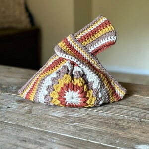 Crochet sunburst knot bag pattern. This beautiful motif crochet pattern is versatile and functional. This boho crochet bag pattern features a crochet flower sunburst design that makes this boho handbag really stand out.