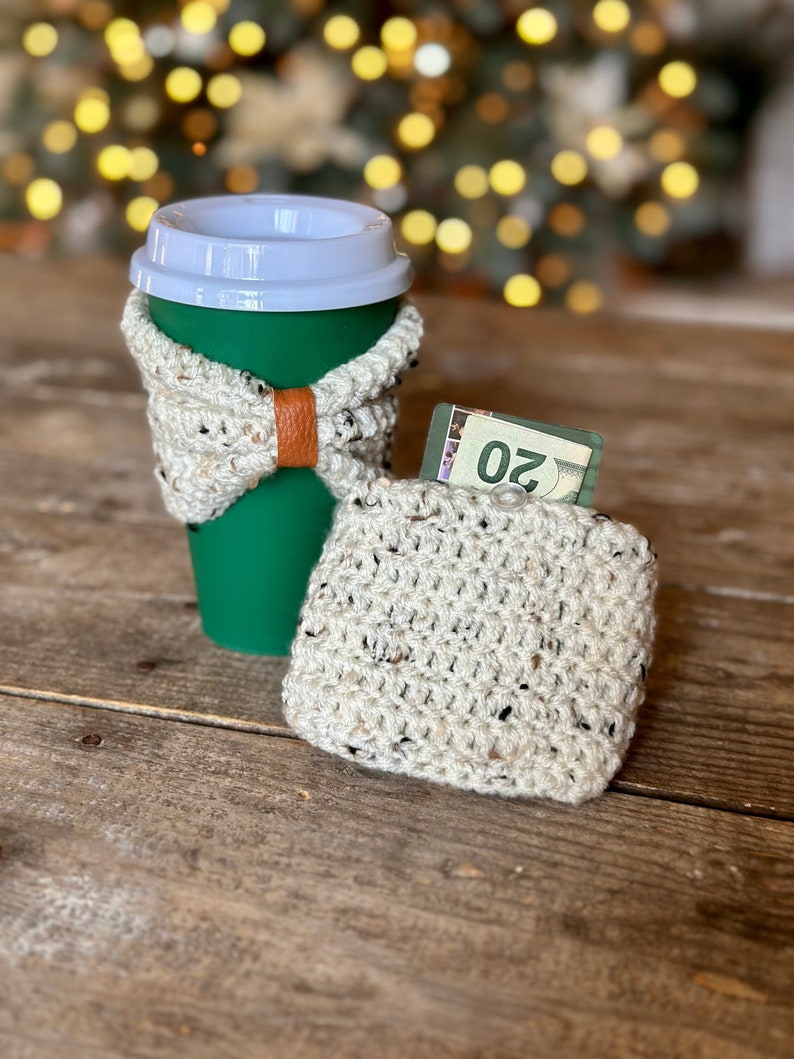 Crochet wrist wallet that doubles as a cup cozy with money in the pocket portion and one on a reusable coffee cup.