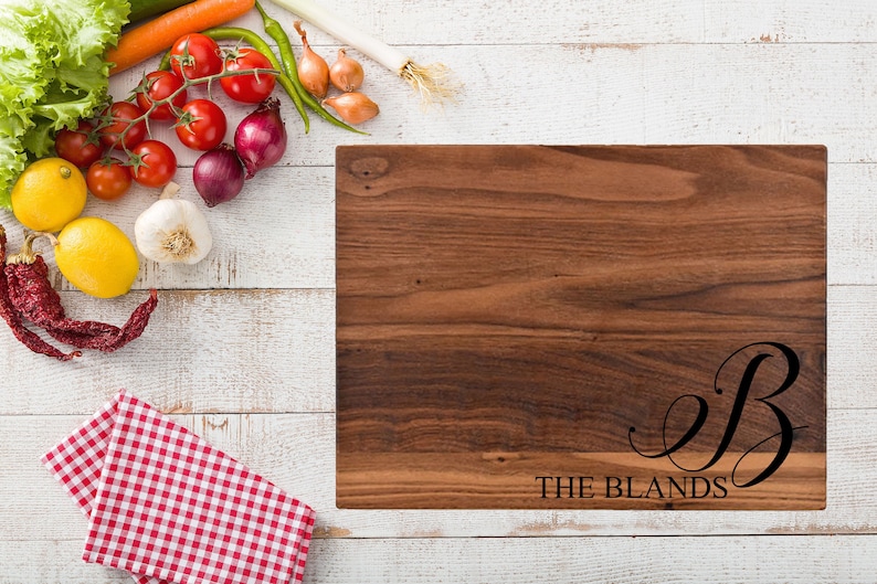 May include: A personalized walnut wood cutting board with the text "THE BLANDS" and a cursive letter "B" engraved on the surface.