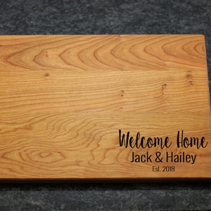 K&ouml;nnte beinhalten: Ein Schneidebrett aus Holz mit dem eingravierten Text "Welcome Home Jack & Hailey Est. 2018".