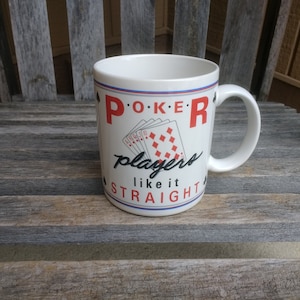 May include: White ceramic coffee mug with a red, black and blue design. The mug says "Poker players like it straight" with a graphic of playing cards.