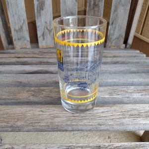 以下が含まれることがあります： 街並みを表す青と黄色のデザインが施された透明なガラスのコップ。"Old Mill Creek"という文字が書かれている。