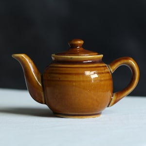 Vintage caramel glaze teapot. ‘Brown Betty’ style. Small sized. Ceramic. One serving. Pottery. Circa early 20th century.