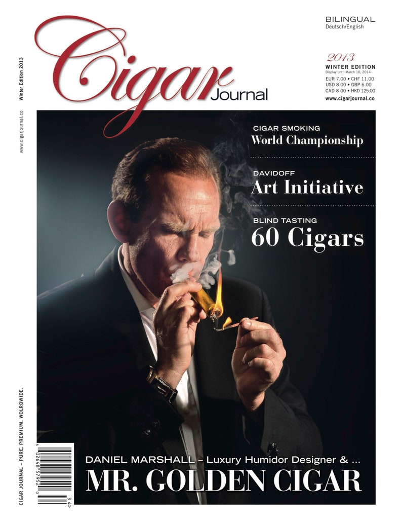 May include: A man in a black suit and white shirt is holding a lit cigar. The magazine cover features the text "Cigar Journal", "World Championship", "Davidoff Art Initiative", "Blind Tasting 60 Cigars", and "Daniel Marshall - Luxury Humidor Designer & ... MR. GOLDEN CIGAR".