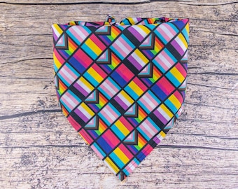 May include: A triangular bandana with a black background and a geometric pattern of colourful squares. The squares are in shades of pink, purple, blue, yellow, and white.