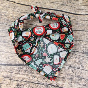 May include: A black bandana with a Christmas-themed print featuring red, green, and white illustrations of cookies, cocoa, candy canes, and other holiday treats. The text "Cookies for Santa" is printed on the bandana.