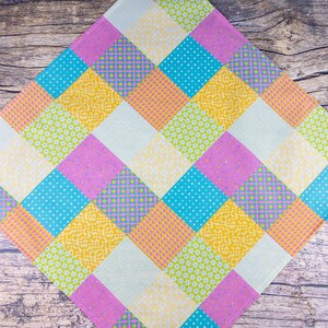 May include: A colorful patchwork quilt featuring a diamond pattern. The quilt showcases squares in various pastel colors, including pink, yellow, blue, and green. Some squares have floral or polka dot patterns, while others are solid.