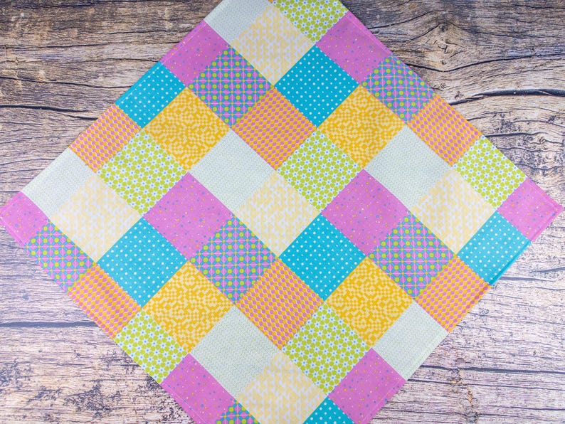 May include: A colorful patchwork quilt featuring a diamond pattern. The quilt showcases squares in various pastel colors, including pink, yellow, blue, and green. Some squares have floral or polka dot patterns, while others are solid.