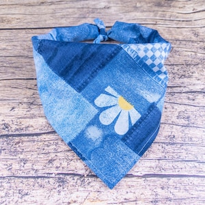 May include: A blue bandana with a white daisy and checkered pattern. The bandana is tied in a knot at the top.