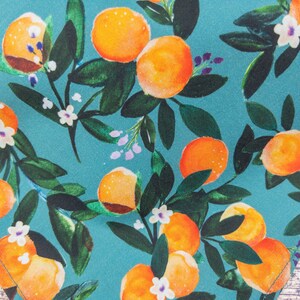 May include: Teal fabric with a repeating pattern of orange citrus fruit and white flowers. The fabric has a watercolor-like design.