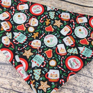 May include: Black fabric with a repeating pattern of Santa Claus mugs, cookies, candy canes, and Christmas trees. The fabric has the text "Cookies for Santa" in a red circle.