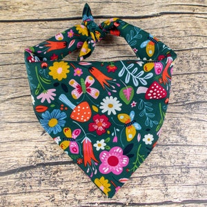 May include: A green bandana with a colorful floral and butterfly print. The bandana is tied in a knot at the top.