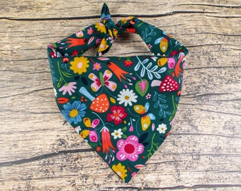 May include: A green bandana with a colorful floral and butterfly print. The bandana is tied in a knot at the top.