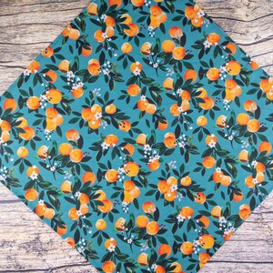 May include: A teal blue fabric with a repeating pattern of orange oranges and white flowers. The fabric is perfect for crafting projects like quilting, sewing, and making accessories.