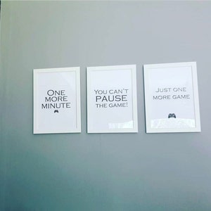 Pode incluir: Tr&ecirc;s impress&otilde;es emolduradas com molduras brancas e texto preto. As impress&otilde;es dizem: "ONE MORE MINUTE", "YOU CAN'T PAUSE THE GAME!" e "JUST ONE MORE GAME". Cada impress&atilde;o apresenta um pequeno &iacute;cone de controle.